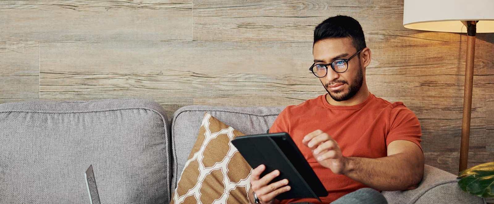 a man sitting on a couch working on his tablet